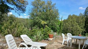 Outdoor seating with a table and chairs, surrounded by trees and greenery. - La Corsica (Sillans-la-Cascade)