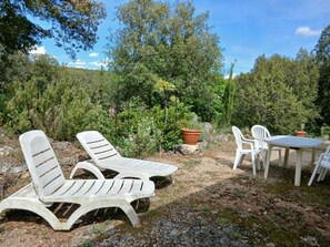 Outdoor seating with a table and chairs, surrounded by trees and greenery. - La Corsica (Sillans-la-Cascade)