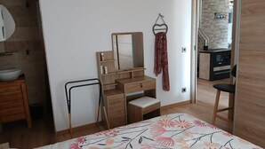 A bedroom with a bed, a dresser, a mirror, and a bathroom with a sink and shower. - La Corsica (Sillans-la-Cascade)