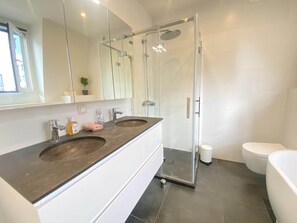 A modern bathroom with a glass-enclosed shower, dual sinks, and a toilet. - Modern Antwerp City Centre Stay (Antwerp)