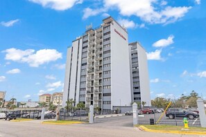 A multi-story hotel with a modern design, featuring balconies on each floor. - Seascape Cove at Holiday Towers 605 elevator/pool (Myrtle Beach)