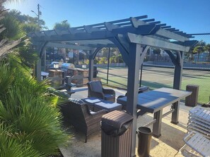 An outdoor seating area with wicker furniture and a pergola structure. - Seascape Cove at Holiday Towers 605 elevator/pool (Myrtle Beach)