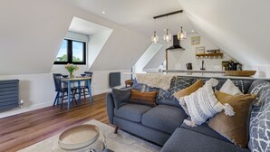 A loft-style living space with a dining area, a sofa, and a kitchen. - Ferny Retreat -  Romantic barn conversion, Hay-On-Wye (Bromyard)