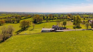 A rural landscape with rolling hills, a farmhouse, and a fenced property. - Ferny Retreat -  Romantic barn conversion, Hay-On-Wye (Bromyard)