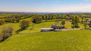 A rural landscape with rolling hills, a farmhouse, and a fenced property. - Ferny Retreat -  Romantic barn conversion, Hay-On-Wye (Bromyard)