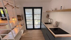 Ett kompakt kök med en central köksö, en inbyggd ugn och ett fönster med frostat glas.