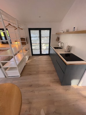 Una cocina compacta con una isla central, horno empotrado y ventanal con puertas de vidrio esmerilado.
