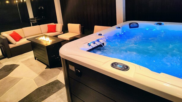 Un jacuzzi con panel de control, un sofá con cojines rojos y una chimenea.