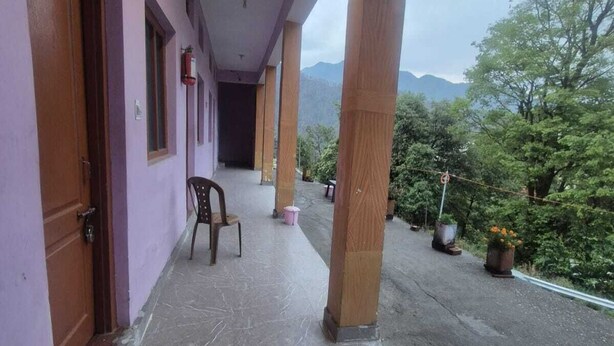 Un pasillo cubierto con vistas a montañas, pilares de madera y una silla.