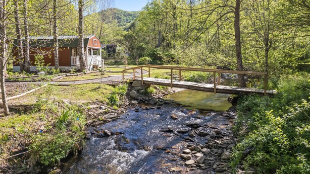 Una cabaña rústica con una terraza de madera y un puente sobre un arroyo.