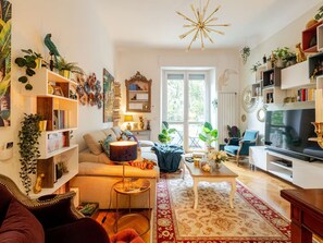 A living room with a sofa, coffee table, TV, and various decorative items. - Tropical Chic Flat Near the Centre, 15 minutes to Duomo (Milano)