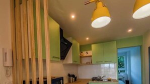 A modern kitchen with green cabinets, wooden countertops, and yellow pendant lights. - Private Room in a Shared Apartment - Bron (Bron)