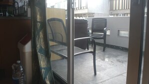 A balcony with two chairs, a water bottle, and a view of buildings. - Designer 5-Bedroom Home by Elizabeth Line (Greater London)