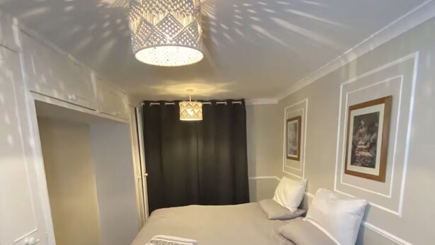A bedroom with a bed, a chair, a door, and a ceiling light fixture. - Designer 5-Bedroom Home by Elizabeth Line (Greater London)