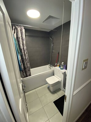 A bathroom with a bathtub, a shower, a toilet, and a sink. - Designer 5-Bedroom Home by Elizabeth Line (Greater London)