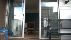 A sliding glass door leading to a room with a wooden chair and a black mesh chair. - Designer 5-Bedroom Home by Elizabeth Line (Greater London)