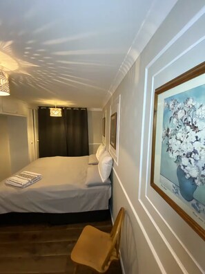 A hotel room with a bed, a chair, a painting, and a window with curtains. - Designer 5-Bedroom Home by Elizabeth Line (Greater London)