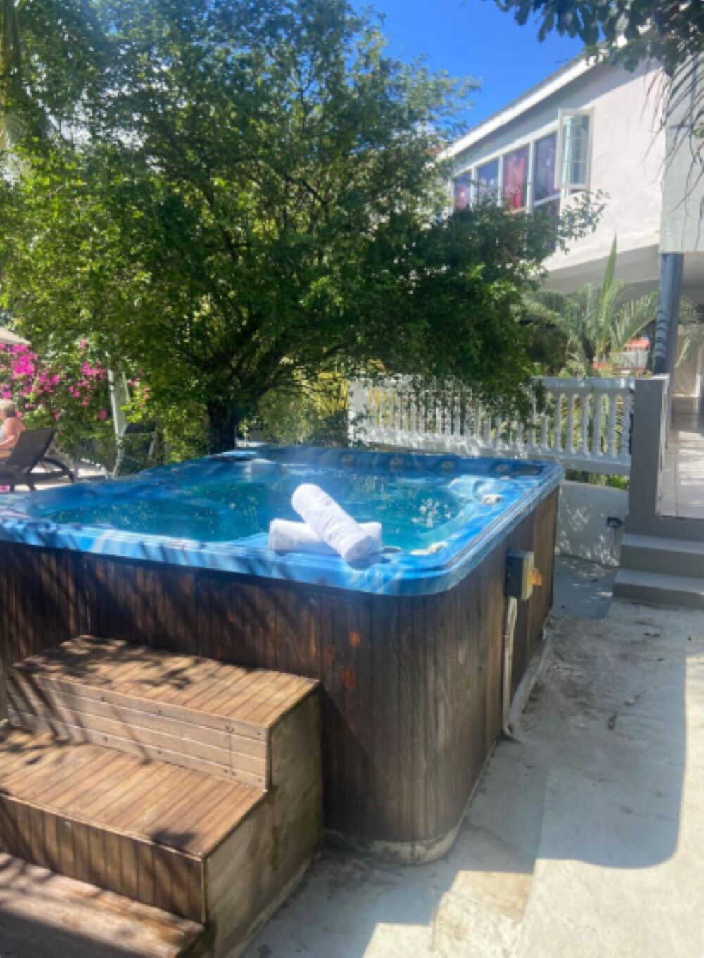 Ein Whirlpool mit einer Holzbank, umgeben von Bäumen und einem Haus.
