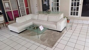 A living room with a white sectional sofa, a glass coffee table, and a tiled floor. - 1-Bdrm Studio Retreat in Rodney Bay w AC (Gros Islet)