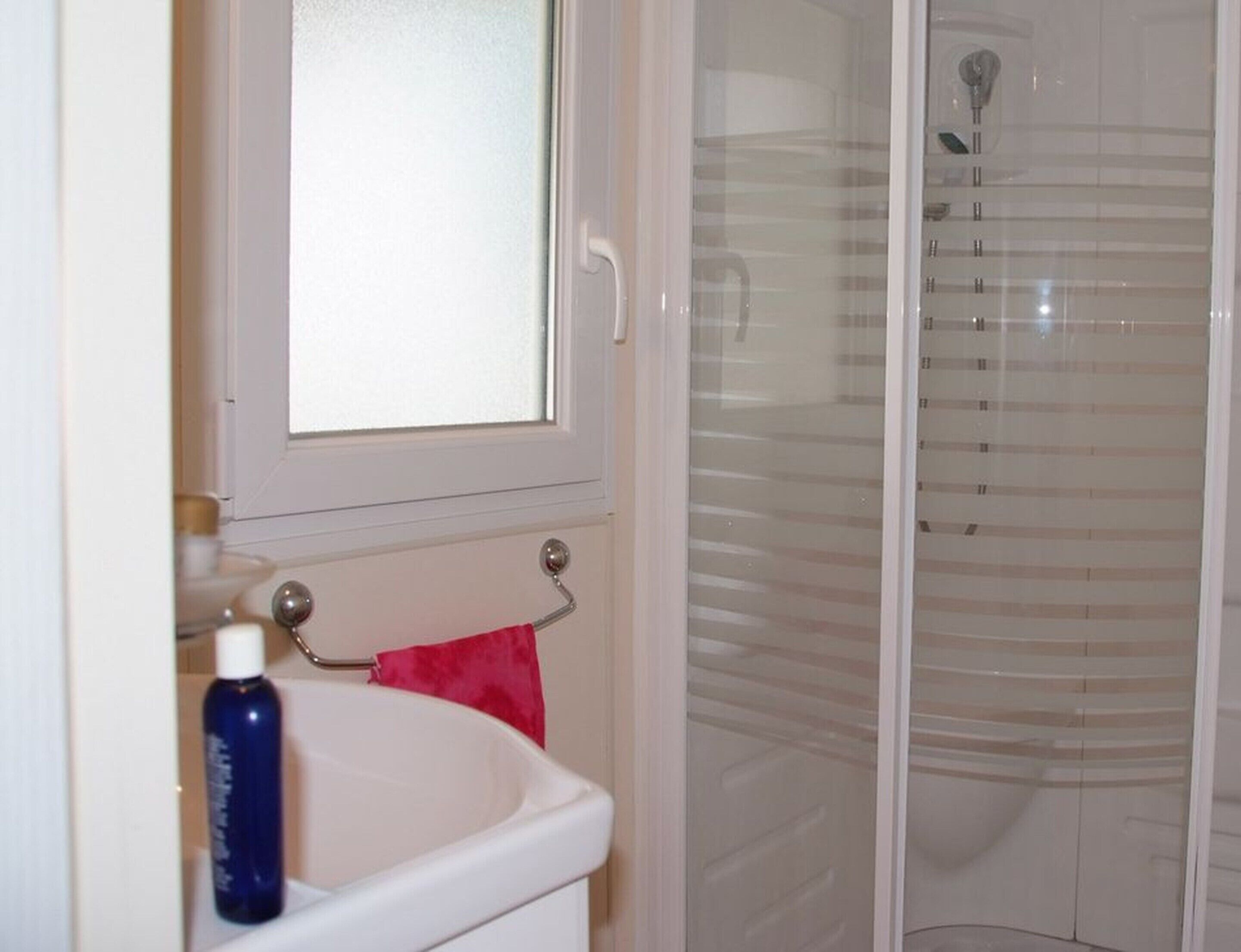 Une salle de bain avec un lavabo blanc, un miroir et une cabine de douche en verre.