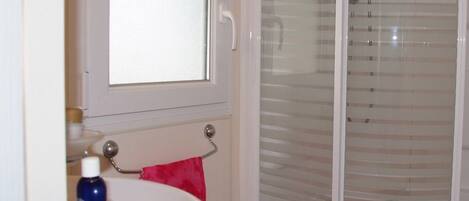 Une salle de bain avec un lavabo blanc, un miroir et une cabine de douche en verre.