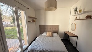 Un dormitorio con cama, mesita de noche, lámpara colgante y vistas a través de la puerta corrediza.