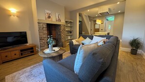 Een woonkamer met een televisie, bank, open haard en een trap naar een ander niveau.