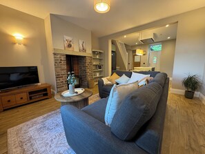 Ein Wohnzimmer mit Fernseher, Sofa, Kamin und einer Treppe zu einer weiteren Ebene.