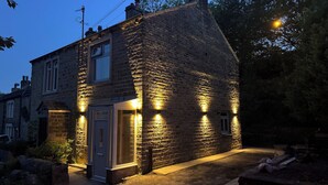 Een gebouw van steen met een deur en ramen, verlicht door buitenverlichting.