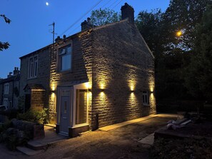 Ein Steinhaus mit Tür und Fenstern, beleuchtet durch Außenbeleuchtung.