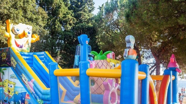 Un’attrazione gonfiabile con scivolo, parete da arrampicata e area giochi separata.