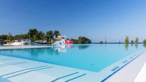 Una piscina azzurra e limpida con uno scivolo acquatico e una torretta per bagnini.