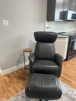 A modern kitchen with a black leather chair, a small round table, and a built-in oven.