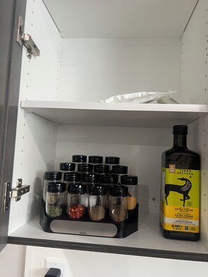 A kitchen cabinet with a spice rack and a bottle of extra virgin olive oil.