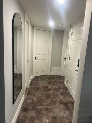 A hallway with white doors, a large mirror, and a marble floor.