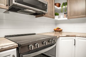 A kitchen with a stove, oven, microwave, and white cabinets.