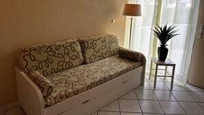 Un soggiorno con un divano, un tavolino con una pianta e tre quadri appesi al muro.