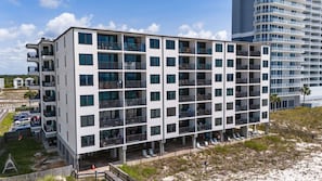 Ein mehrstöckiges Hotel mit Balkonen, einem Poolbereich und Blick auf den Strand.