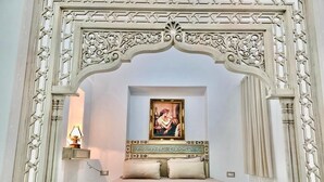 Una cama con cabecera, un cuadro colgado en la pared y una mesita de noche con lámpara.