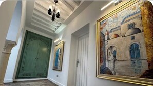 Un pasillo con una puerta verde, una puerta blanca y un cuadro enmarcado en la pared.