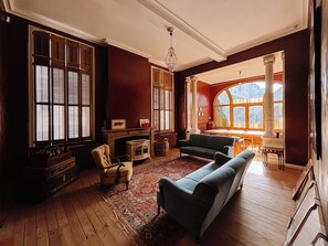 A spacious living room with a fireplace, large windows, and a view of the outdoors.