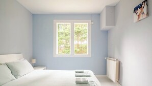 A bedroom with a bed, a window, a radiator, and a painting on the wall. - Peace 3 bed gîte (Chevanceaux)
