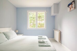 Ein Schlafzimmer mit einem Bett, einem Fenster, einer Heizung und einem Bild an der Wand.