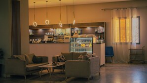 Un moderno vestíbulo de hotel con una zona de estar, un bar y un gran ventanal con cortinas.