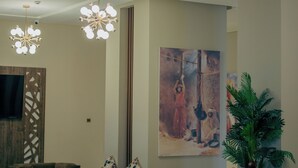 Un vestíbulo con muebles modernos, un cuadro abstracto de gran tamaño y una planta en maceta.