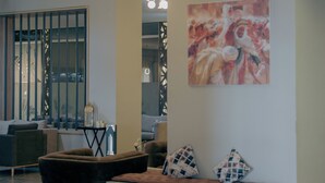 Un vestíbulo moderno con un banco, un cuadro abstracto de gran tamaño y una lámpara decorativa.