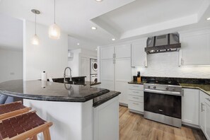 A modern kitchen with a central island, stainless steel appliances, and pendant lighting. - Coastal Chill - Air-Conditioning, Near Race Track, Beach, Pool (Solana Beach)