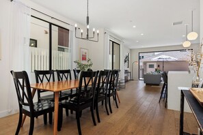 Un comedor con una mesa de madera y sillas negras, una araña y vistas a un balcón con barandilla.