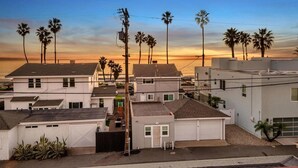 Un quartier résidentiel avec des maisons, des palmiers et une vue sur le coucher du soleil.