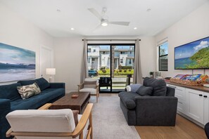 Una sala de estar moderna con un sofá, un sillón, una mesa de centro y un televisor.